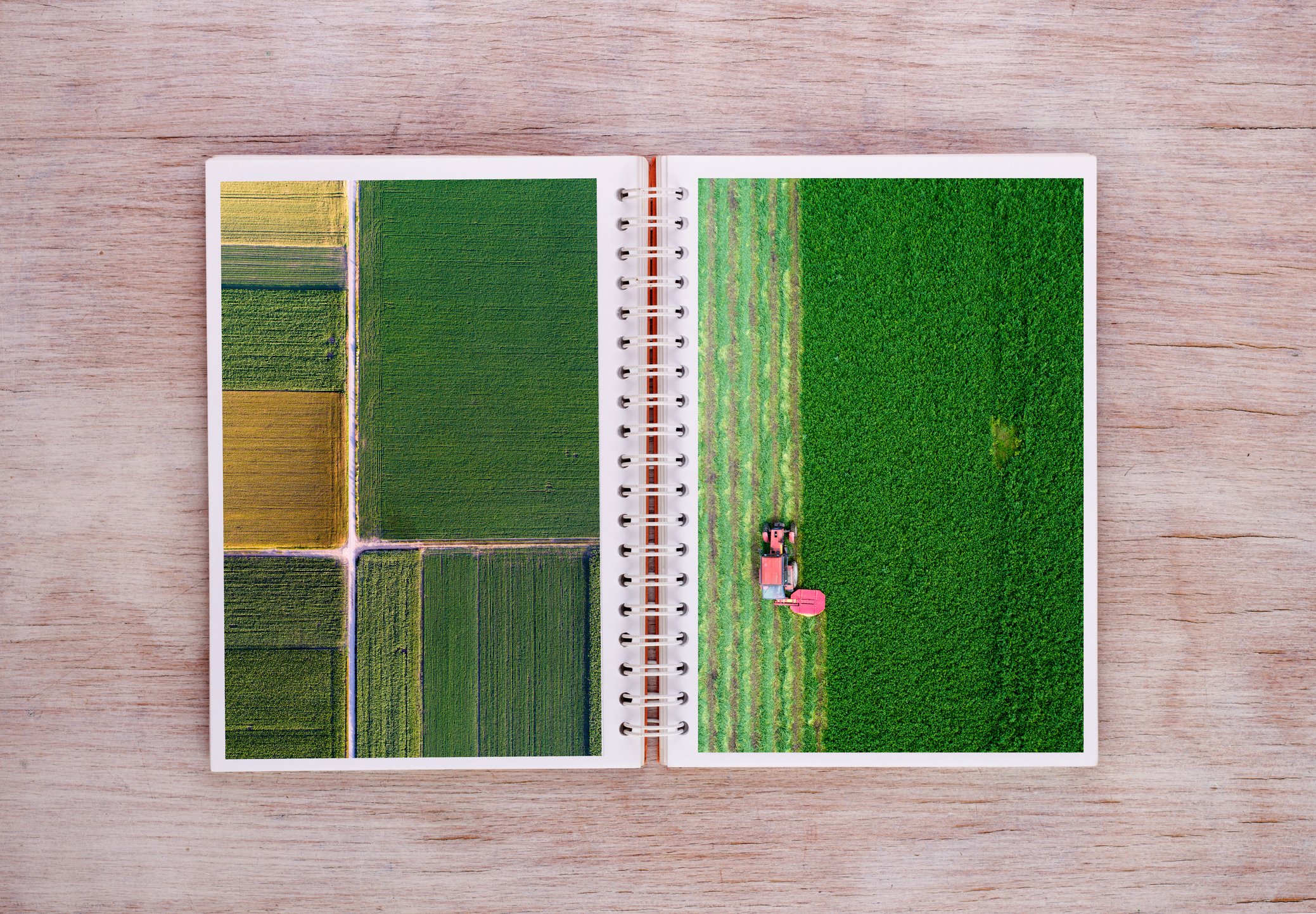 An open book on a desk with a tractor and green fields