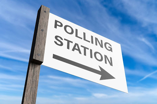 Polling station sign against a blue sky backdrop