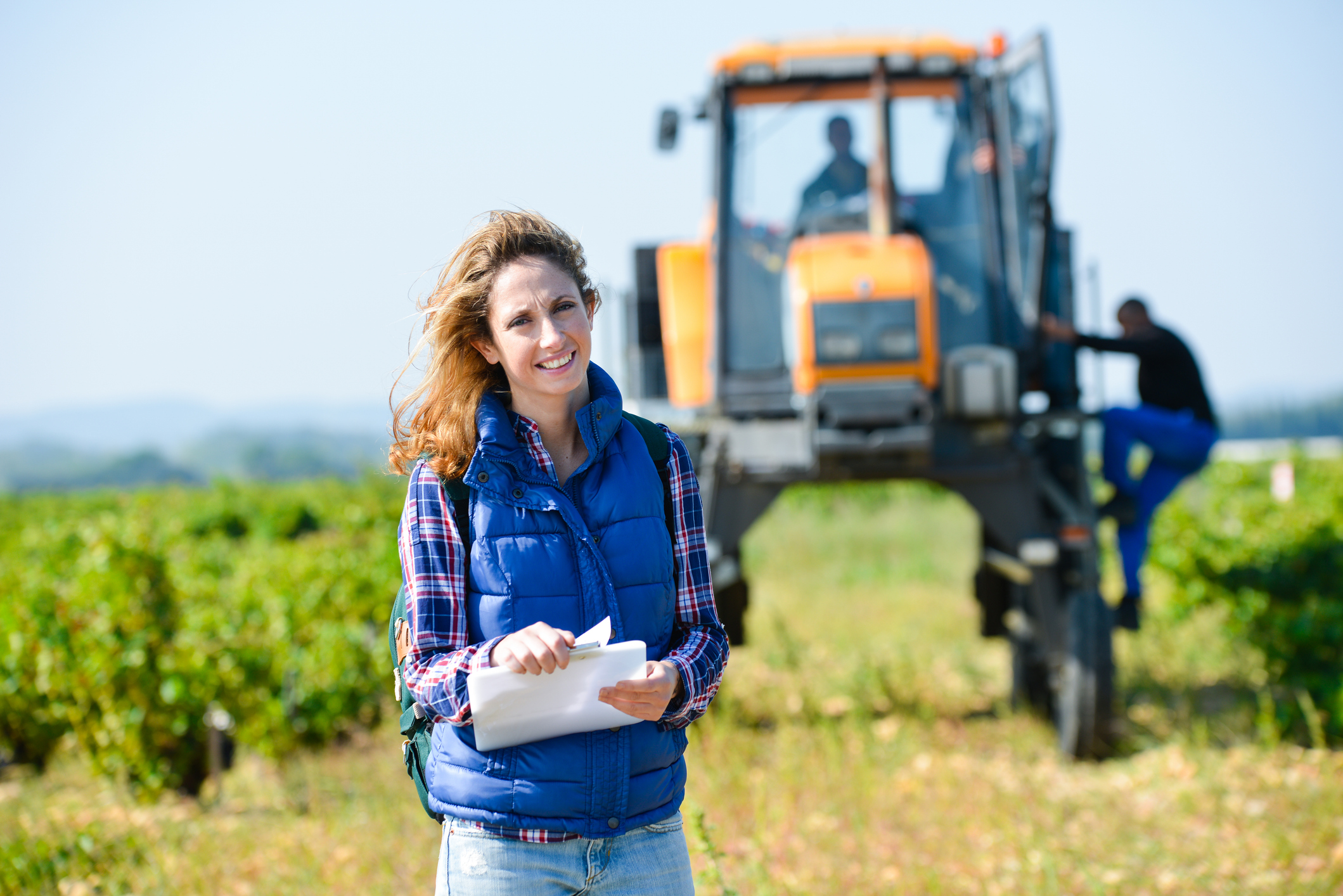 Woman Farmer on a farm with a yellow tractor behind her