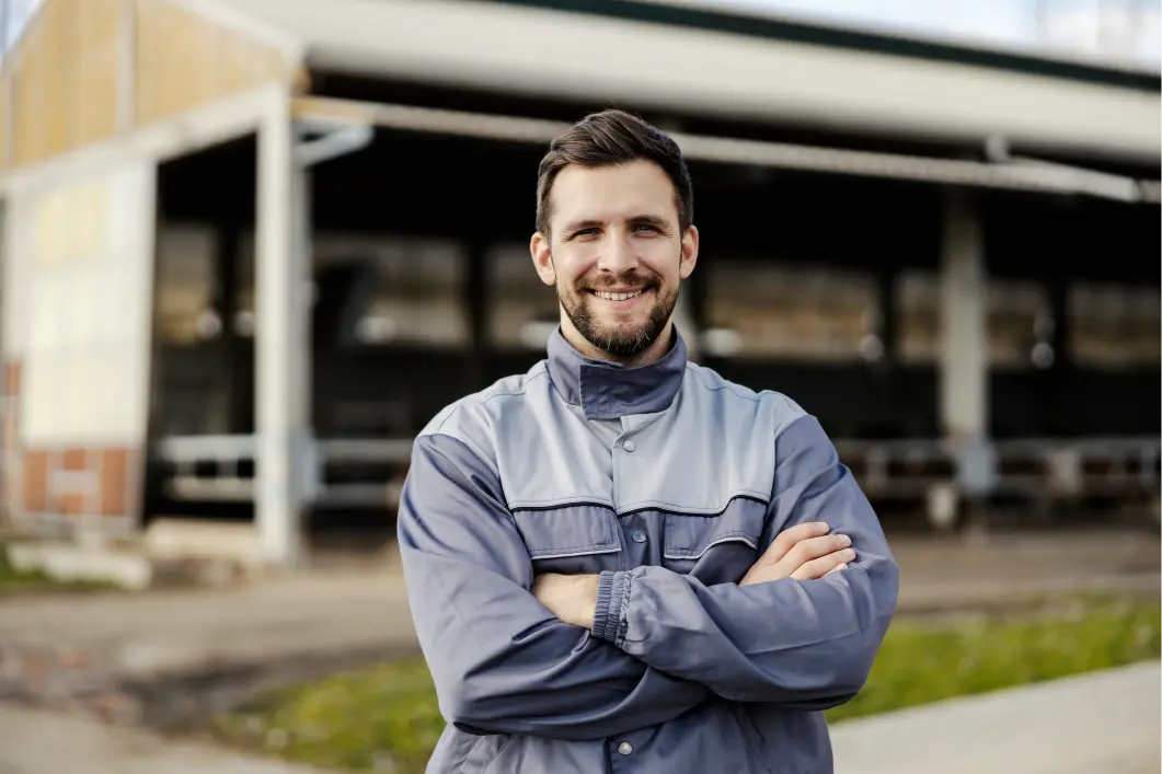 Happy farmer standing outside a farm building shed