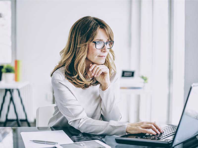 Business woman in glasses at a desk looking at her computer