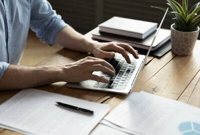 Someone typing at a desk on a laptop